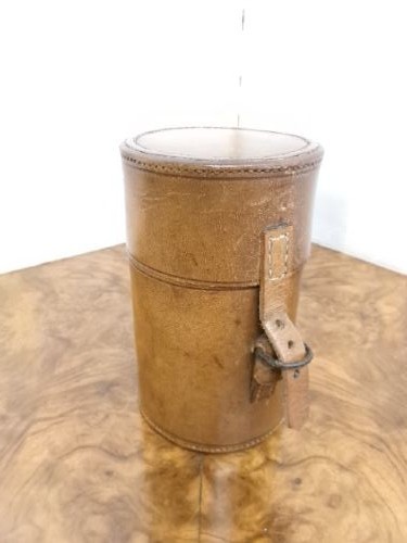 A cylindrical tan leather case opened to reveal four glass flasks fitted with polished silver domed caps. View II