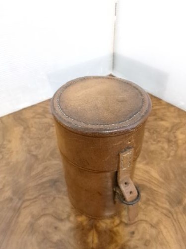 A cylindrical tan leather case opened to reveal four glass flasks fitted with polished silver domed caps. View III