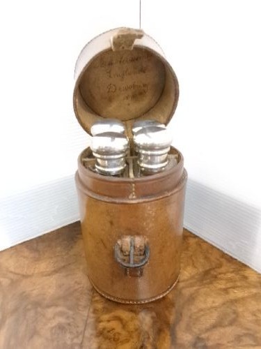 A cylindrical tan leather case opened to reveal four glass flasks fitted with polished silver domed caps. View XI
