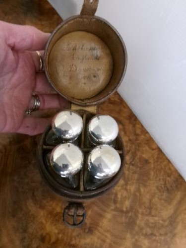 A cylindrical tan leather case opened to reveal four glass flasks fitted with polished silver domed caps. View VIII