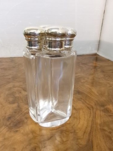 A cylindrical tan leather case opened to reveal four glass flasks fitted with polished silver domed caps. View VII