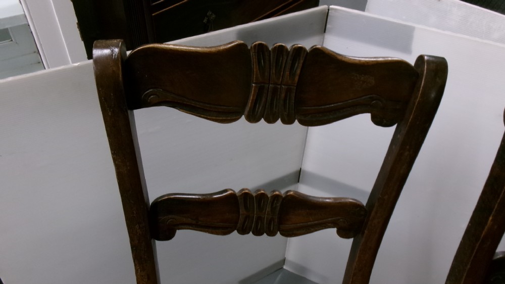 A pair of late Victorian dark brown wooden kitchen chairs with carved back rails, saddled wooden seats, and turned front legs. View III