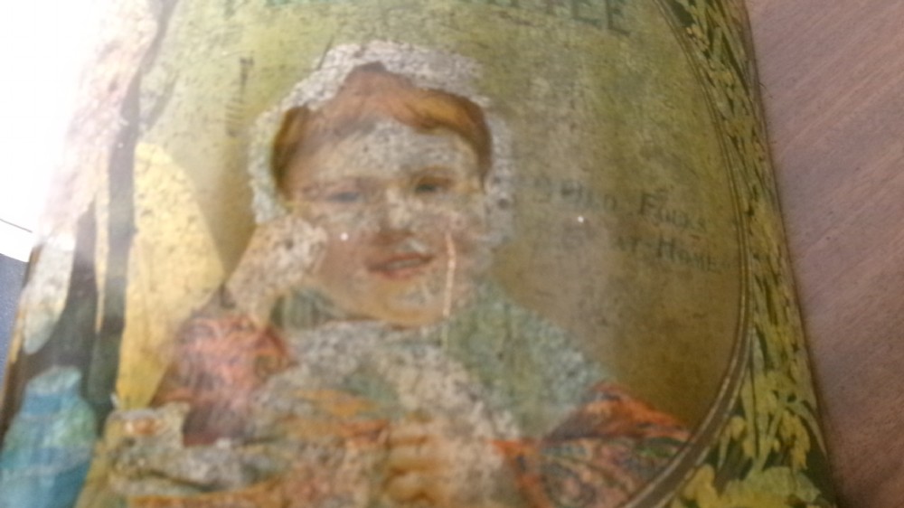 An antique semi-circular green tinplate tea caddy featuring a lithographed illustration of a woman drinking tea within an oval frame. View IX
