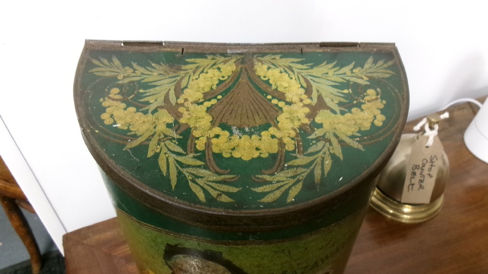 An antique semi-circular green tinplate tea caddy featuring a lithographed illustration of a woman drinking tea within an oval frame. View X