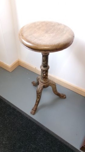 A Victorian revolving stool featuring a circular wooden seat mounted on a cast iron tripod base.
