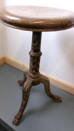 A Victorian revolving stool featuring a circular wooden seat mounted on a cast iron tripod base. View VII