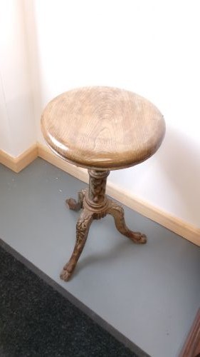 A Victorian revolving stool featuring a circular wooden seat mounted on a cast iron tripod base. View IX