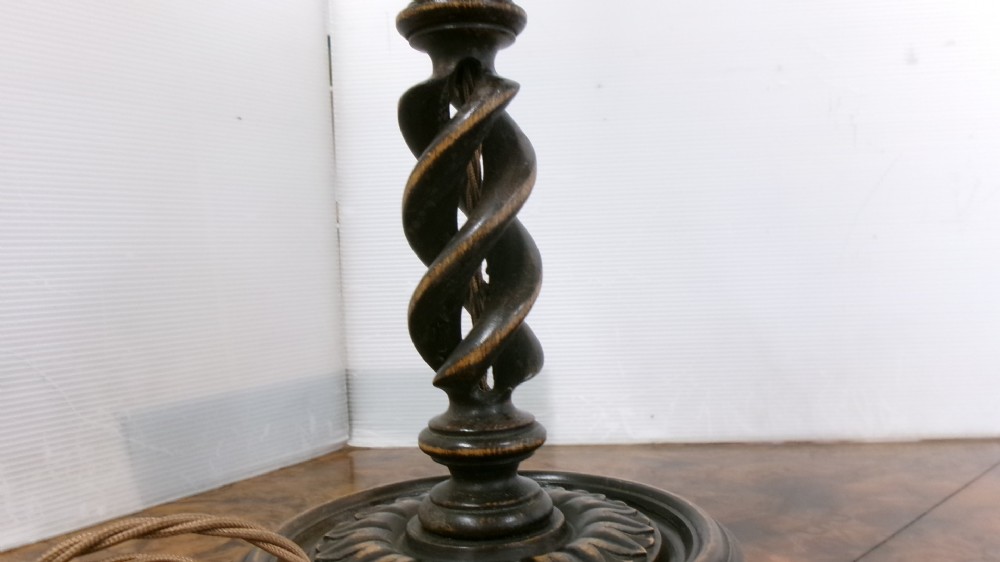 A pair of dark wood table lamps featuring carved barley twist stems, circular bases, and patterned fabric shades with fringed trim. View V