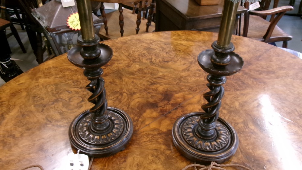 A pair of dark wood table lamps featuring carved barley twist stems, circular bases, and patterned fabric shades with fringed trim. View VII