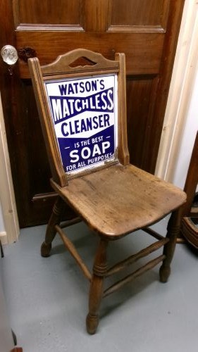 An antique wooden side chair with turned legs featuring an integrated blue and white enamel advertising sign for Watsons Matchless Cleanser Soap set into the backrest.