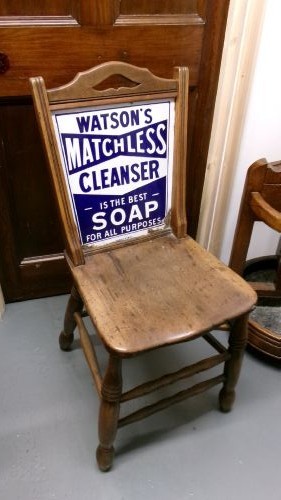 An antique wooden side chair with turned legs featuring an integrated blue and white enamel advertising sign for Watsons Matchless Cleanser Soap set into the backrest. View II