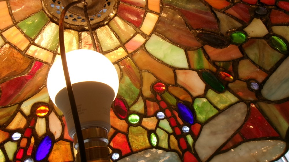 A tall Edwardian brass table lamp featuring an open twist stem and a Tiffany style stained glass dragonfly lampshade. View IV