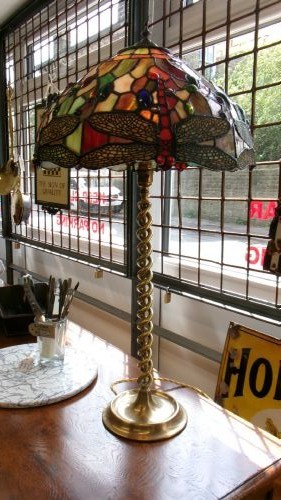 A tall Edwardian brass table lamp featuring an open twist stem and a Tiffany style stained glass dragonfly lampshade.