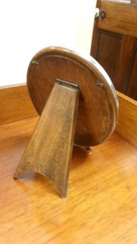 An oval sterling silver photo frame with a plain border, two ball feet, and a wooden backing. View IV