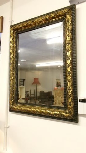 A rectangular Victorian wall mirror featuring a dark wooden frame bordered with ornate gilt brass foliate leaf moulding.