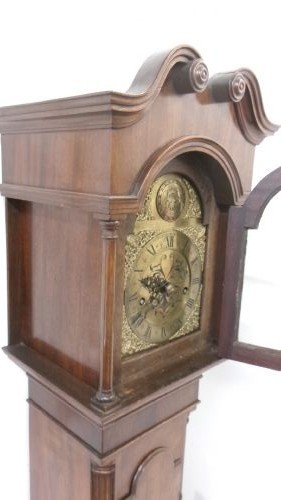 A slim mahogany granddaughter clock featuring a swan neck pediment hood, brass dial with spandrels, and an arched trunk door. View IV