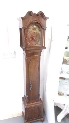 A slim mahogany granddaughter clock featuring a swan neck pediment hood, brass dial with spandrels, and an arched trunk door. View VIII