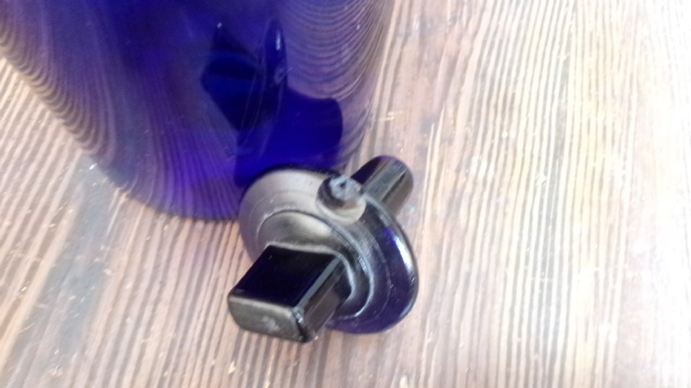 A tall Victorian cobalt blue glass apothecary bottle featuring a dark glass lollipop stopper and a gilt-bordered shield label inscribed SYR VIOLAE. View VI