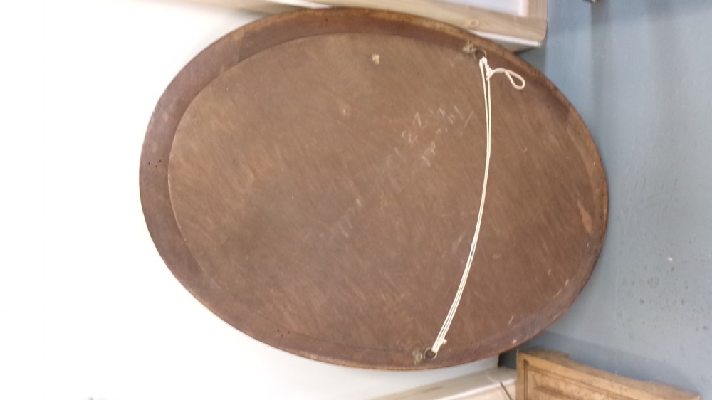 An Edwardian oval wall mirror crafted from mahogany timber featuring a carved decorative outer rim and bevelled glass. View V
