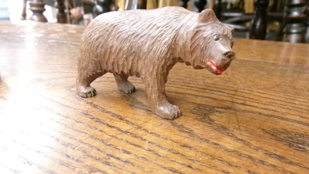 A hand-carved brown wooden bear figurine featuring textured fur, stud eyes, and an open painted red mouth.