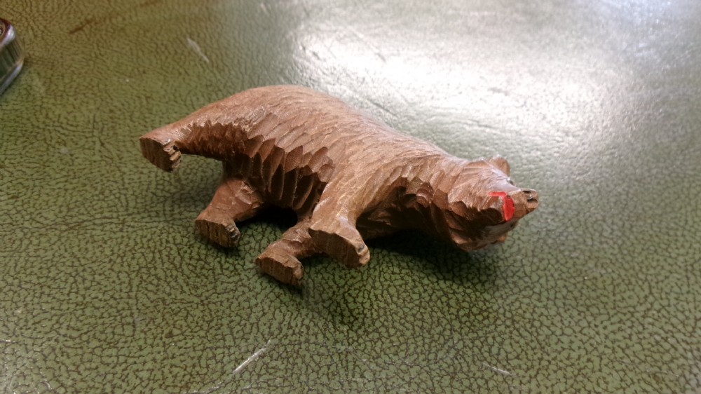 A hand-carved brown wooden bear figurine featuring textured fur, stud eyes, and an open painted red mouth. View III