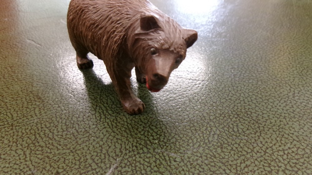 A hand-carved brown wooden bear figurine featuring textured fur, stud eyes, and an open painted red mouth. View VI