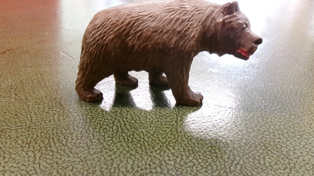 A hand-carved brown wooden bear figurine featuring textured fur, stud eyes, and an open painted red mouth. View VII