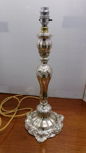 An Edwardian silver-plated table lamp base featuring Rococo scrollwork, a shaped baluster stem, and a moulded plinth base. View VII
