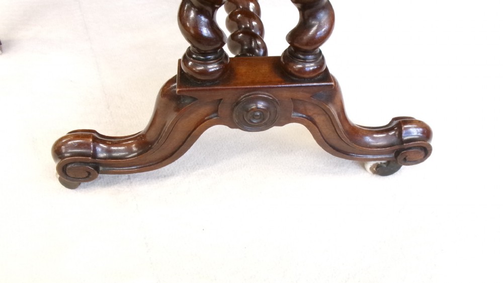 A Victorian burr walnut Sutherland table featuring hinged drop leaves, spiralled barley twist legs, and white ceramic castors. View IV
