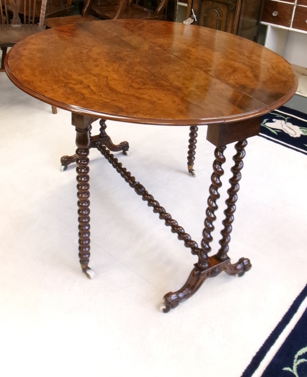 A Victorian burr walnut Sutherland table featuring hinged drop leaves, spiralled barley twist legs, and white ceramic castors. View VI