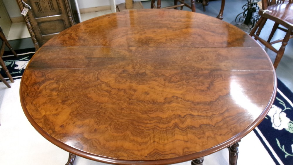 A Victorian burr walnut Sutherland table featuring hinged drop leaves, spiralled barley twist legs, and white ceramic castors. View VII