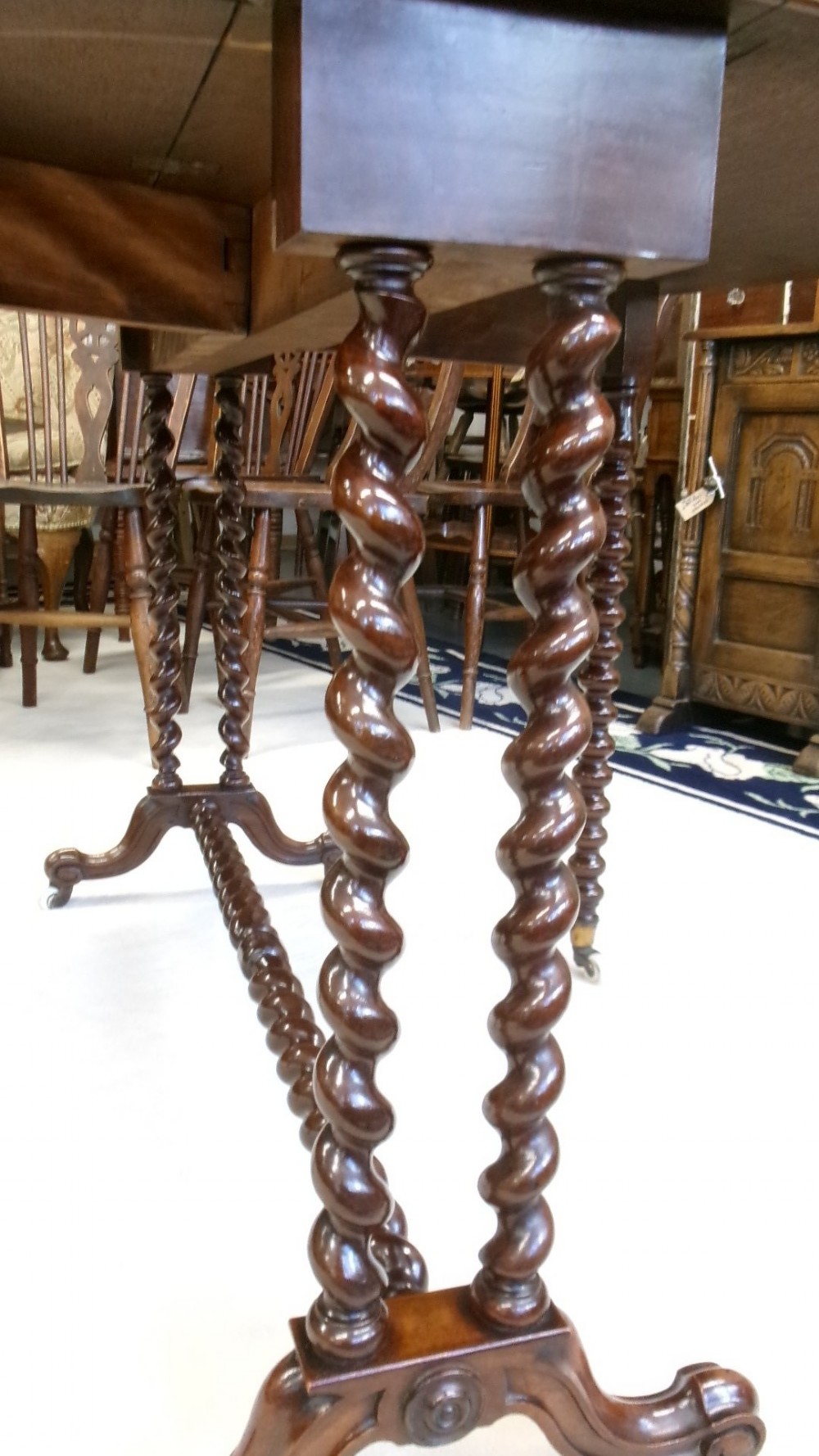 A Victorian burr walnut Sutherland table featuring hinged drop leaves, spiralled barley twist legs, and white ceramic castors. View V