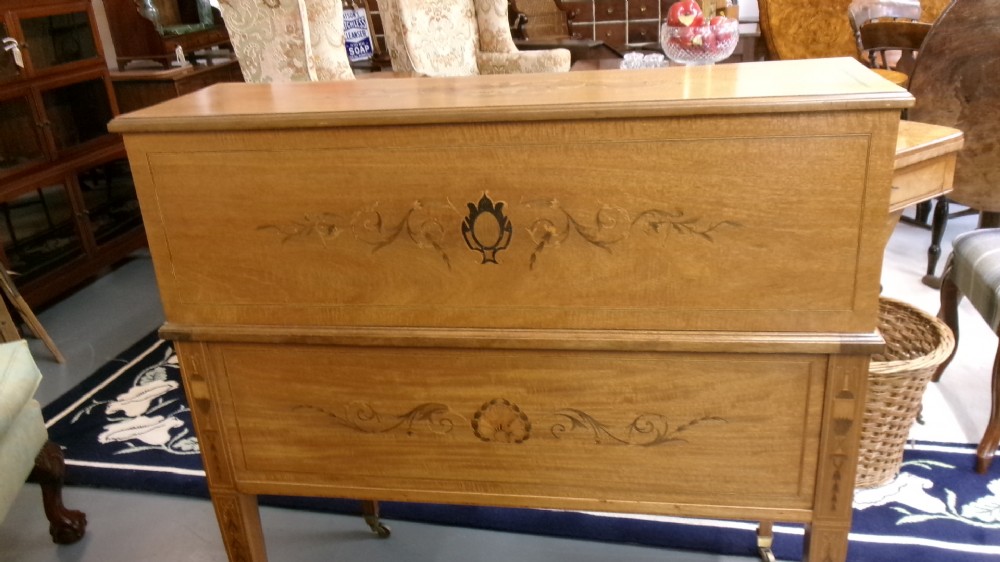 An antique Edwardian inlaid mahogany cylinder top writing desk featuring an open curved roll top, fitted internal compartments, a green leather writing surface, and tapered square legs with brass castors. View VII