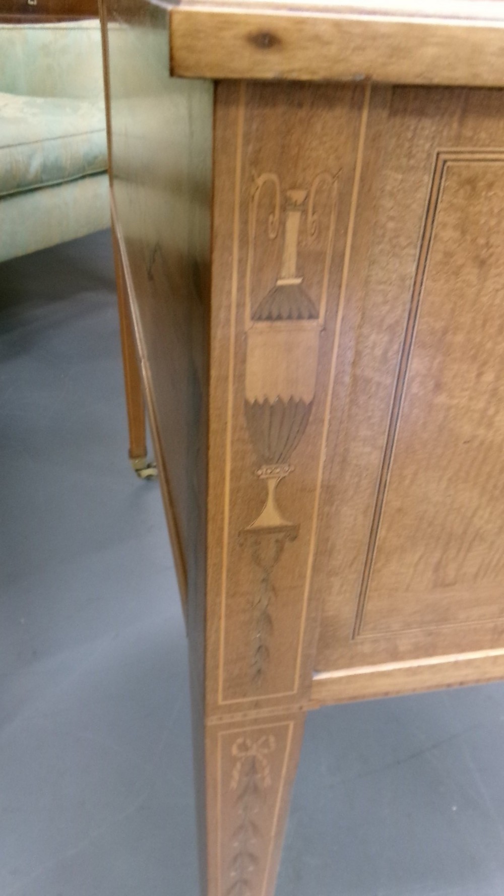 An antique Edwardian inlaid mahogany cylinder top writing desk featuring an open curved roll top, fitted internal compartments, a green leather writing surface, and tapered square legs with brass castors. View V