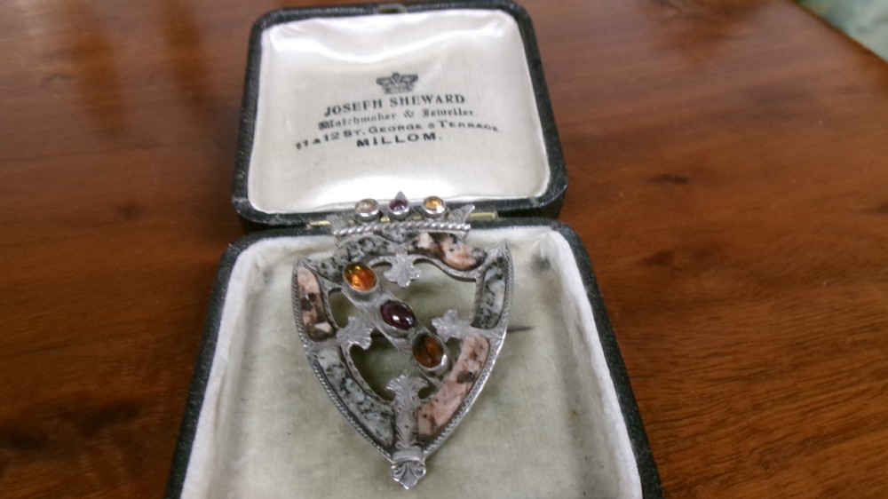 A Victorian silver shield-shaped brooch inlaid with pink and grey agate stones and set with faceted citrines and a central cabochon gemstone. View II