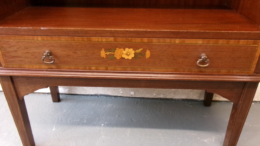 An Edwardian open mahogany bookcase featuring three shelves above a single drawer decorated with floral inlay. View IX