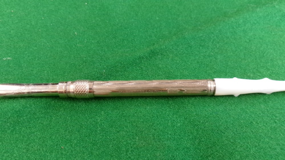 A Victorian Mabie Todd & Co gold-plated dip pen featuring an engraved metal barrel, metal nib, and a carved white handle. View V