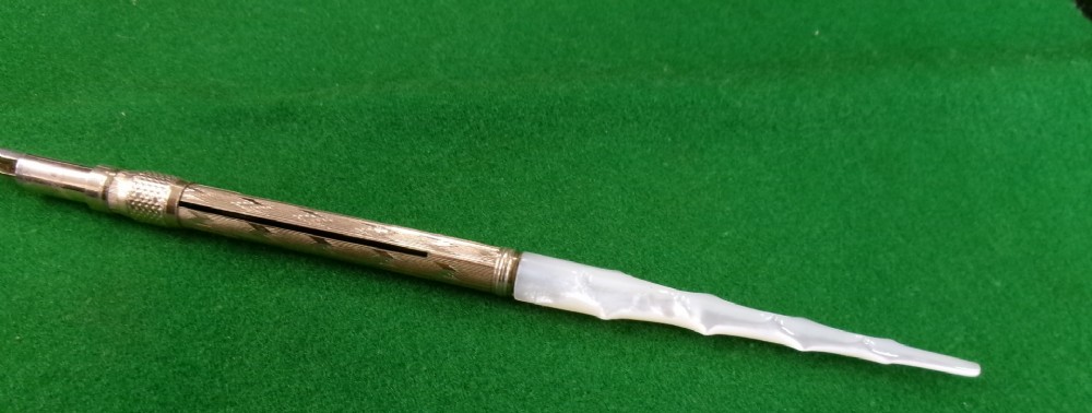 A Victorian Mabie Todd & Co gold-plated dip pen featuring an engraved metal barrel, metal nib, and a carved white handle. View VI