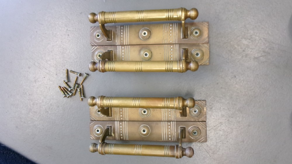 Two pairs of Arts and Crafts brass pull door handles featuring rectangular backplates with incised geometric line detailing and turned cylindrical bar grips with spherical finials. View VII