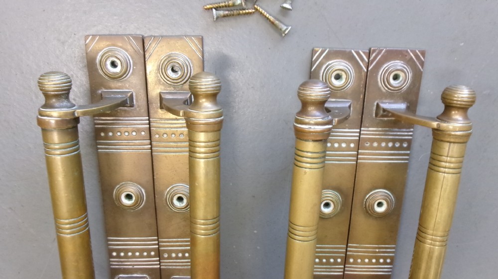 Two pairs of Arts and Crafts brass pull door handles featuring rectangular backplates with incised geometric line detailing and turned cylindrical bar grips with spherical finials. View VIII