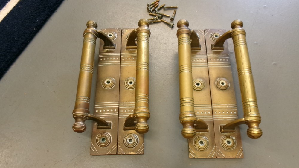 Two pairs of Arts and Crafts brass pull door handles featuring rectangular backplates with incised geometric line detailing and turned cylindrical bar grips with spherical finials. View X