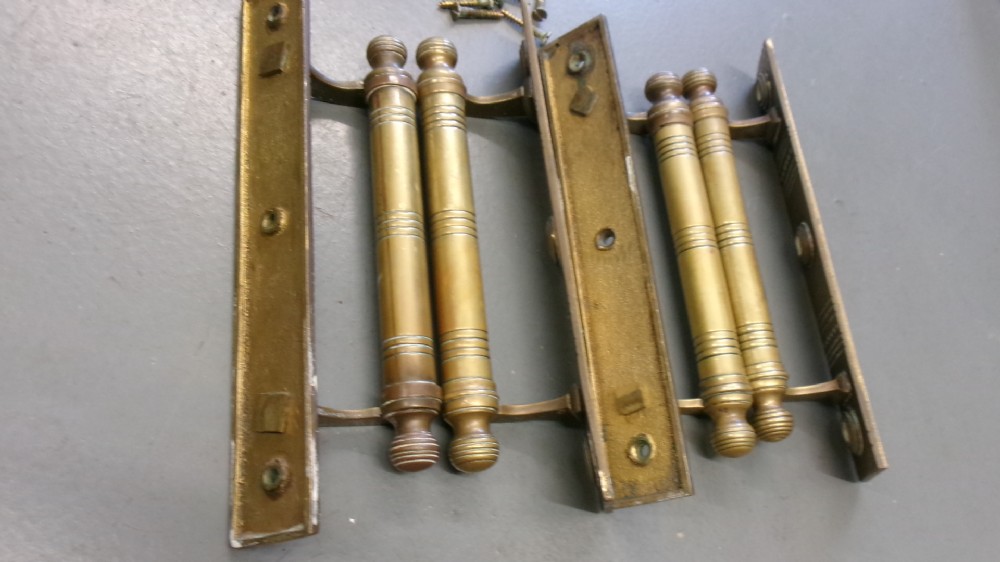 Two pairs of Arts and Crafts brass pull door handles featuring rectangular backplates with incised geometric line detailing and turned cylindrical bar grips with spherical finials. View XII