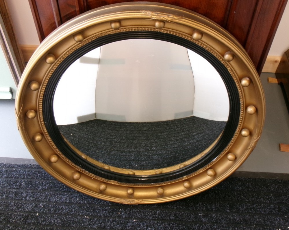 A circular Victorian giltwood convex mirror featuring a ball-decorated outer frame and a black ebonised inner slip.