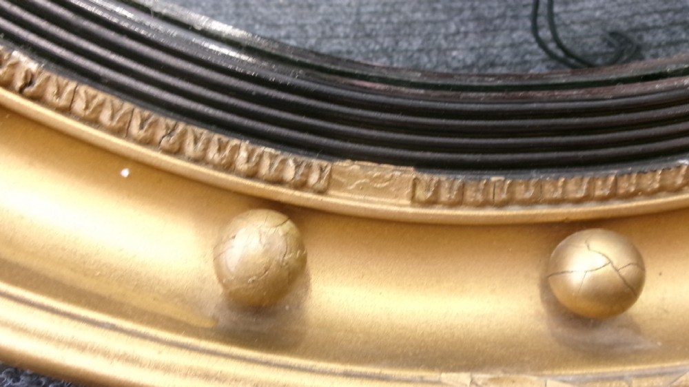 A circular Victorian giltwood convex mirror featuring a ball-decorated outer frame and a black ebonised inner slip. View II