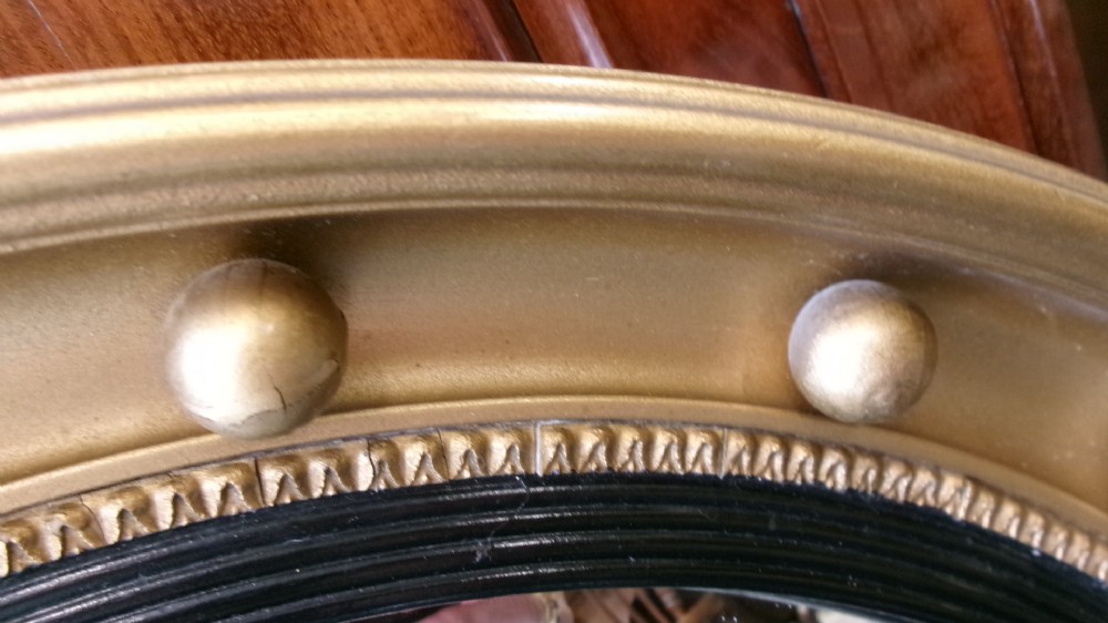A circular Victorian giltwood convex mirror featuring a ball-decorated outer frame and a black ebonised inner slip. View XII