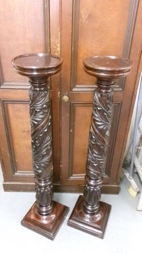 A pair of tall Victorian dark mahogany torchere stands featuring circular dished tops, spiral acanthus leaf carved shafts, and square plinth bases.
