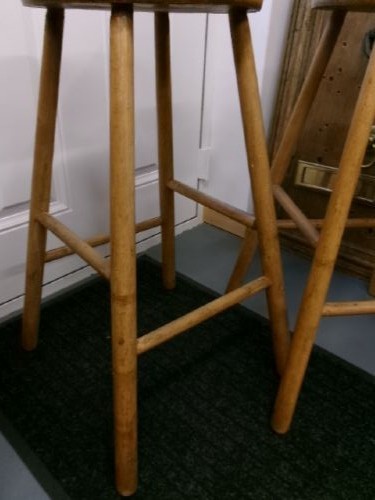 A pair of tall wooden bar stools featuring circular elm seats, splayed turned legs, and lower supporting stretchers. View IV