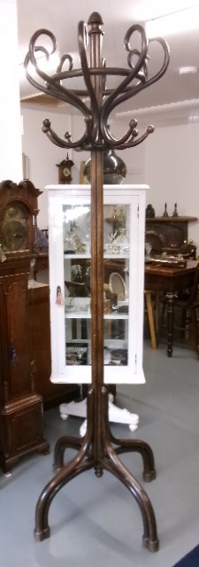 A dark brown bentwood hat and coat stand featuring multiple curved upper hooks, a circular ring, and a four-legged splayed base.