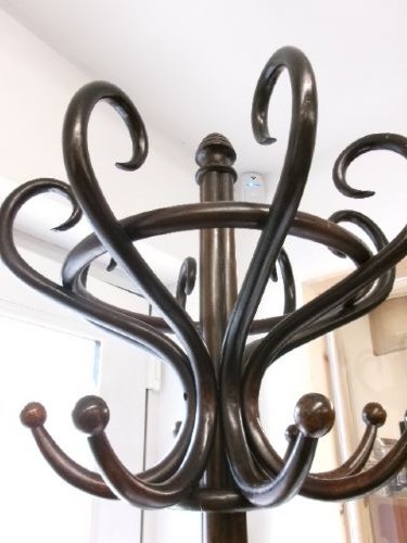 A dark brown bentwood hat and coat stand featuring multiple curved upper hooks, a circular ring, and a four-legged splayed base. View II