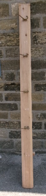 A long vertical pine wood backboard fitted with four double-pronged brass coat hooks.